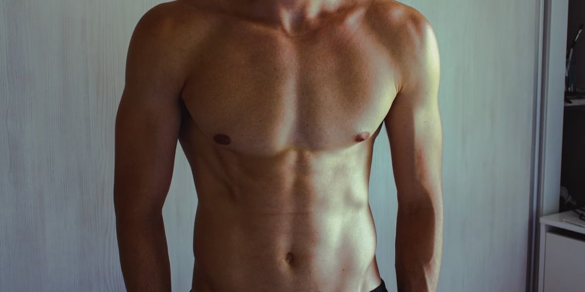 Close-up of athletic shirtless man showcasing muscular and fit physique.