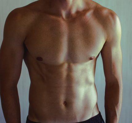 Close-up of athletic shirtless man showcasing muscular and fit physique.