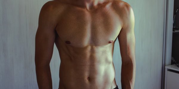 Close-up of athletic shirtless man showcasing muscular and fit physique.