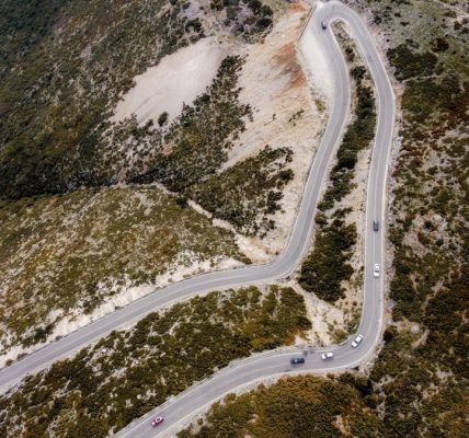 Captivating aerial shot of a winding road through autumn landscapes on a mountain.